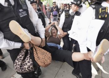 A woman is led away by police officers as supporters of Palestine Action take part in a mass action in Parliament Square, organised by Defend Our Juries as part of the Lift the Ban campaign, to end the proscription of Palestine Action, in London, Saturday, Aug. 9, 2025. (Stefan Rousseau/PA via AP)