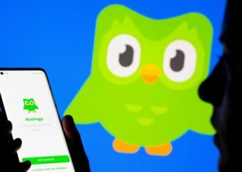 Woman with her smartphone poses in front of displayed Duolingo logo in this illustration taken, June 29, 2021. REUTERS/Dado Ruvic/Illustration