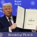 Trump unveils Davos Board of Peace, pitches $1B membership 19 Trump holds an open signed document in front of a blue backdrop reading “Board of Peace.”