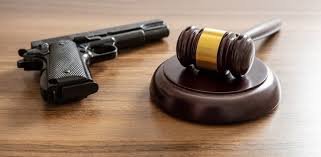 Gavel and handgun on a wooden table representing Canada’s gun buyback program